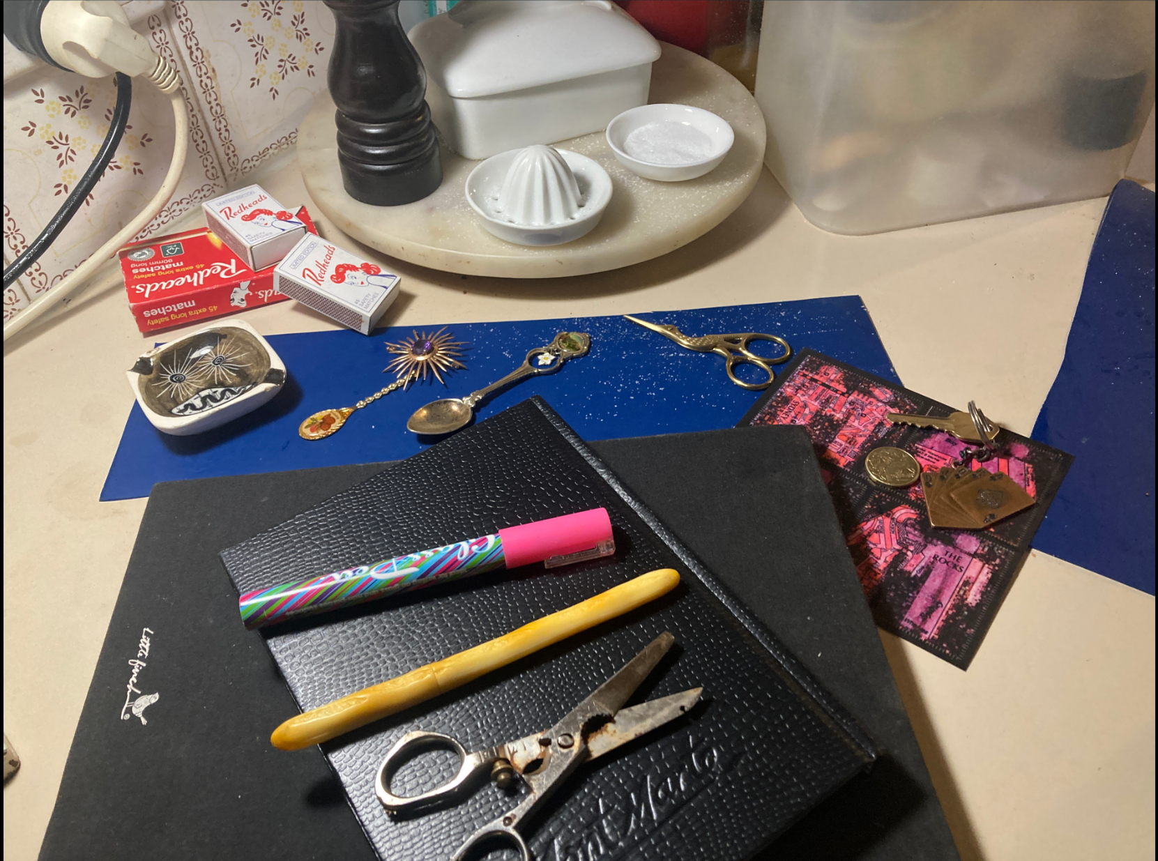 Books, pens, spoons, scissors, Map Art, Pepper Grinder,  matches, keys, one dollar. My Nan and Pops little ashtray with snake, sky, stars... 